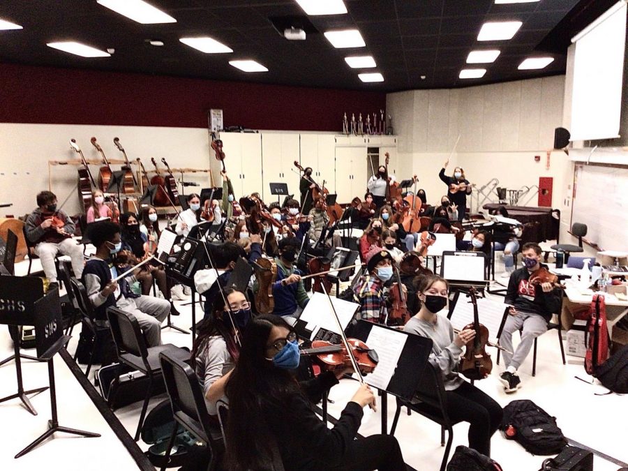 Members of the orchestra practice in person. 