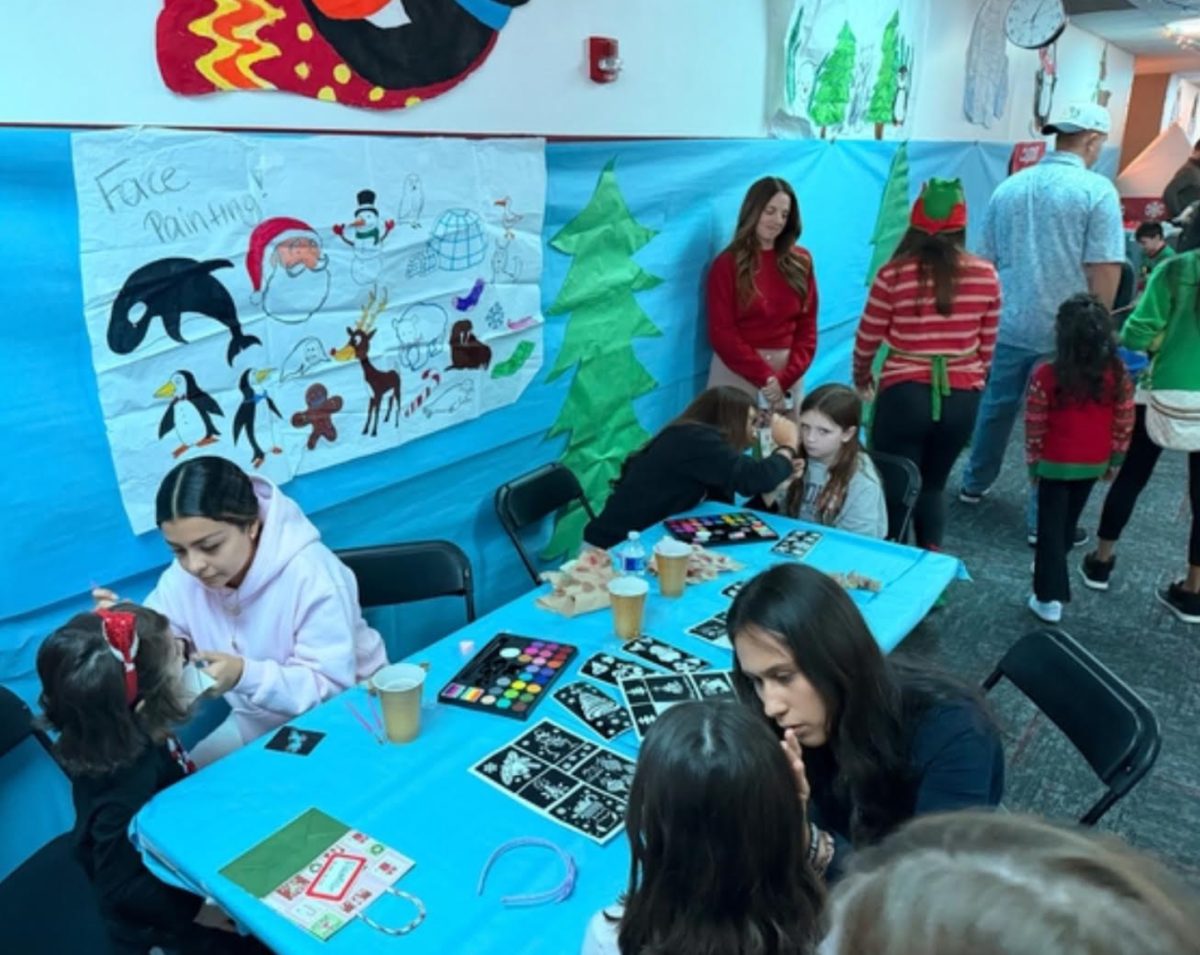 Student volunteers assist children at the face-painting station.