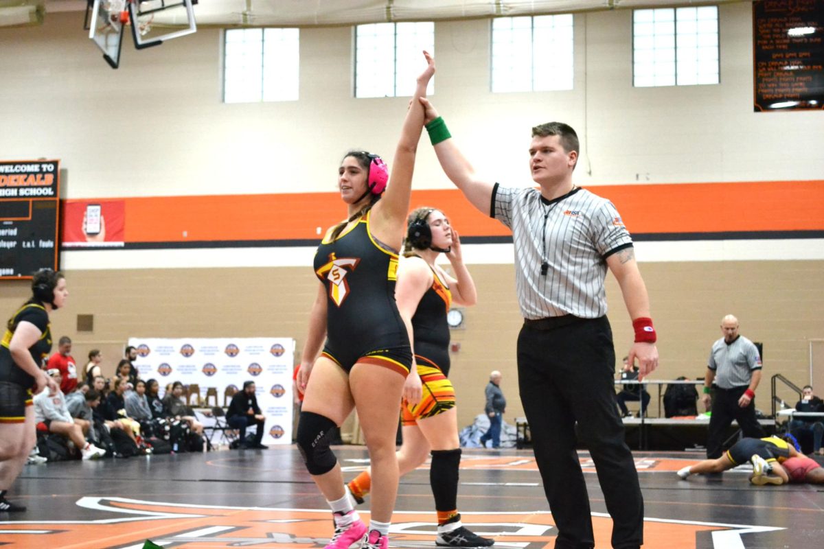 Senior Nadia Razzak raises her arm in victory. Schaumburg wresters brought home two individual and one team medals at state.